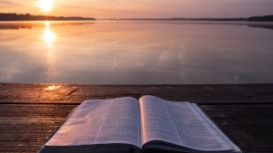 Une Bible ouverte sur une jetée avec un coucher du soleil en arrière-plan