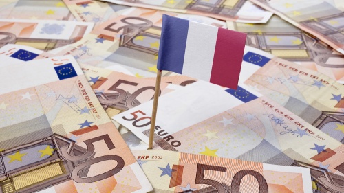Un drapeau français trône sur une tapisserie de billets de banque en euros.