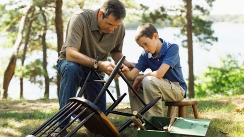 Un fils aide son père à faire du bricolage ; le père enseigne à son fils comment réparer une chaise.