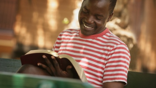 Un homme sourit en lisant sa Bible