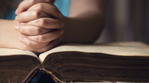 Des mains se tiennent en prière sur une Bible