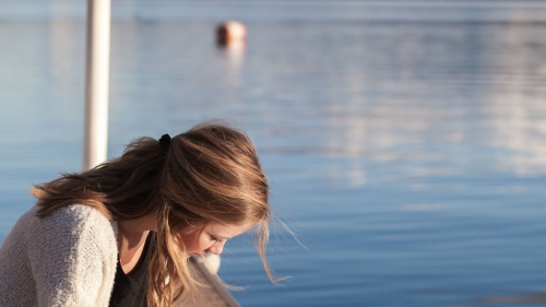 Une fille lit la Bible à côté d'un lac dur un dock