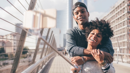Un jeune homme et une jeune femme se tiennent dans les bras et prennent un selfie.