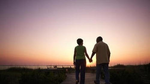 Un couple de personnes âgées marchant sur une planche marche pendant que le soleil se couche.