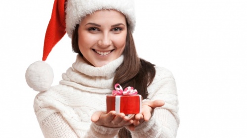 Une femme coiffée d'un bonnet de bas de Noël tenant un cadeau.