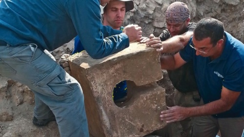 Les ouvriers enlèvent le siège d’une toilette en pierre utilisée pour désacraliser le sanctuaire lorsque l’autel fut découvert.