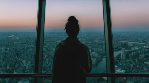 Une fille qui regarde une grande ville par la fenêtre au crépuscule