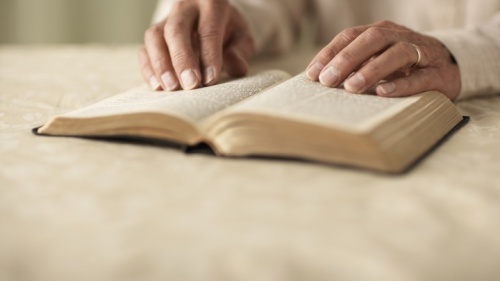 Une Bible avec les mains d'une femme qui la lit placées dessus