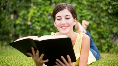 Une femme souriante lit la Bible