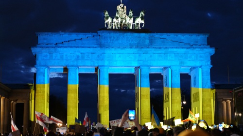 Des manifestants allemands témoignent leur solidarité avec l’Ukraine devant la célèbre porte de Brandebourg, illuminée aux couleurs du drapeau ukrainien.
