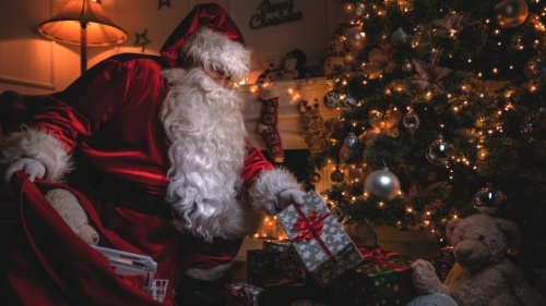 Le Père Noël dépose des cadeaux sous un arbre de Noël.