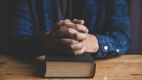 Un homme prie avec une Bible