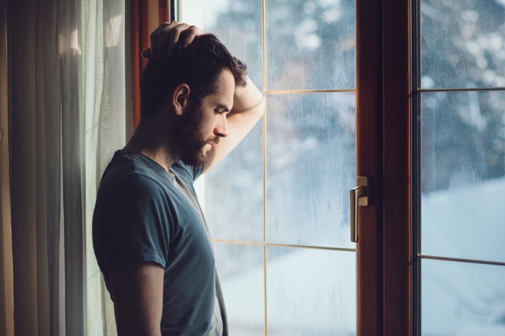 Un homme pensif devant une fenêtre.