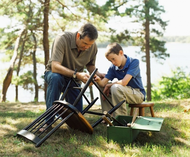 Un fils aide son père à faire du bricolage ; le père enseigne à son fils comment réparer une chaise.