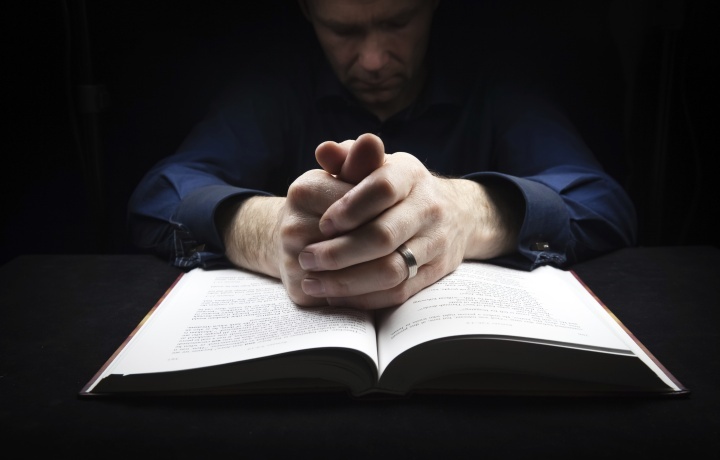 Un homme priant devant une Bible