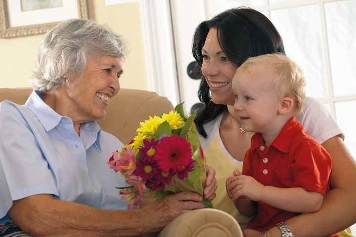 Un petit garçon et sa maman donne des fleurs à sa grand-mère