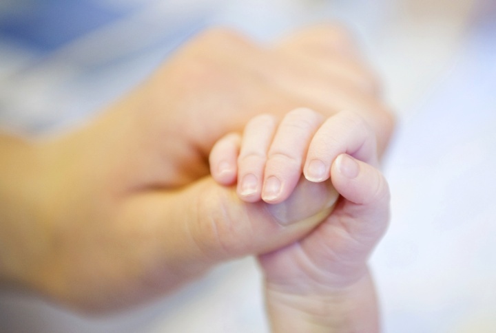 Un parent tient la petite main de son bébé