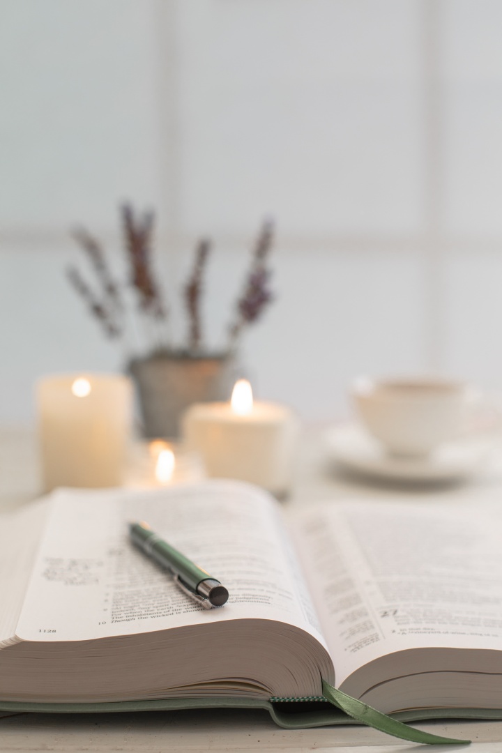 Une Bible et un stylo ; des bougies et une tasse en arrière-plan