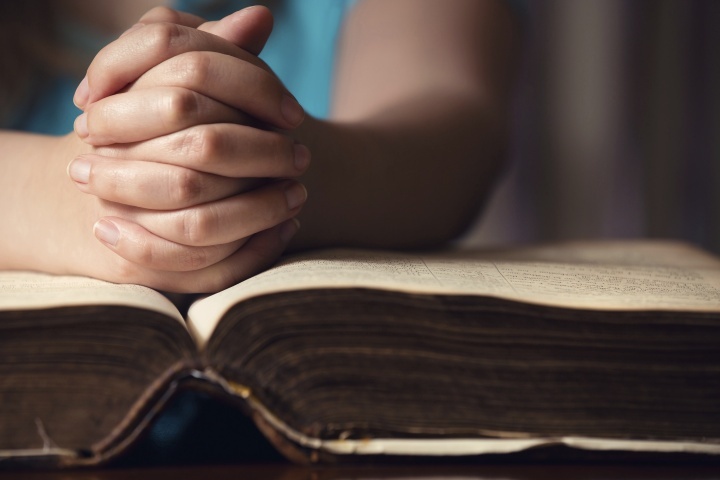 Des mains se tiennent en prière sur une Bible