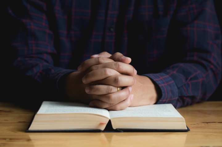 Une personne priant avec une Bible