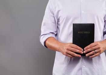 Comment l’OEuvre de Dieu est-elle financée ? Un homme tenant une bible.