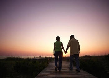 Un couple de personnes âgées marchant sur une planche marche pendant que le soleil se couche.