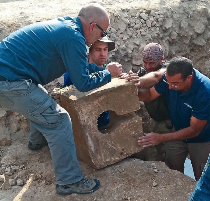 Les ouvriers enlèvent le siège d’une toilette en pierre utilisée pour désacraliser le sanctuaire lorsque l’autel fut découvert.