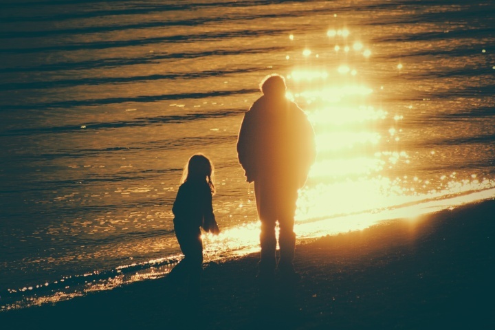 Un père et sa fille font une promenade ensemble au bord du lac au coucher du soleil