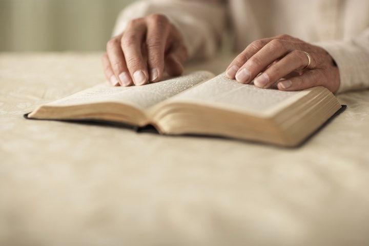 Une Bible avec les mains d'une femme qui la lit placées dessus