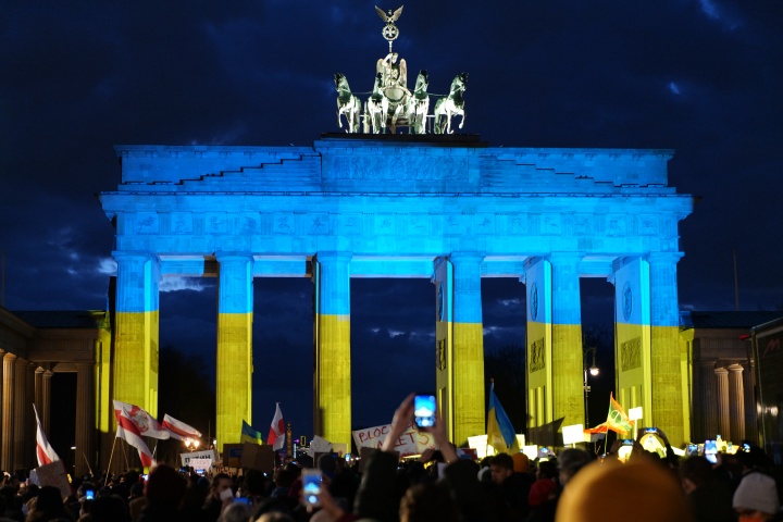 Des manifestants allemands témoignent leur solidarité avec l’Ukraine devant la célèbre porte de Brandebourg, illuminée aux couleurs du drapeau ukrainien.