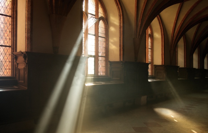 Des rayons de soleil traversent les fenêtres d'une vieille église.