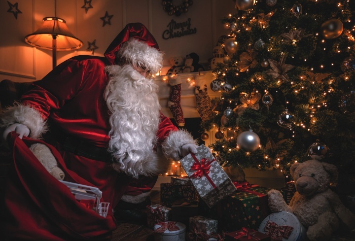 Le Père Noël dépose des cadeaux sous un arbre de Noël.