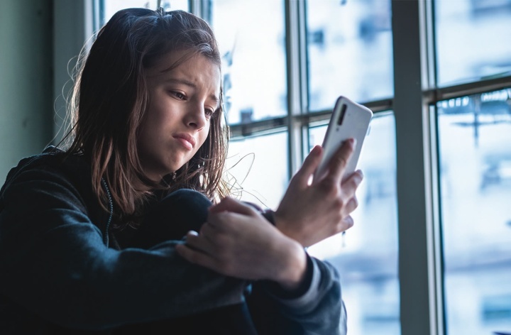 Une adolescente qui regarde son téléphone.