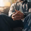 Anxiété, mains et thérapie avec une personne assise sur un canapé dans un cabinet pour un rendez-vous de consultation ou de counseling.