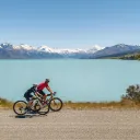 Vue en hauteur d'un homme et sa fille faisant du vélo à côté du lac Pukaki en été