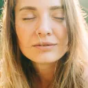 Portrait rapproché d’une femme aux yeux fermés, baignée par une chaude lumière naturelle du soleil