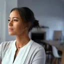 Une femme près d'une fenêtre a l'air déterminée.