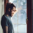 Un homme pensif devant une fenêtre.