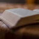 Une Bible à côté des fleurs dans un vase sur une table