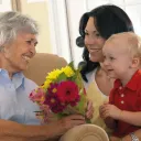 Un petit garçon et sa maman donne des fleurs à sa grand-mère