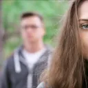 Un jeune couple - femme au premier plan, homme en arrière-plan flou.