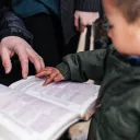 Un petit enfant regarde une Bible