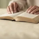 Une Bible avec les mains d'une femme qui la lit placées dessus