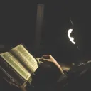Une femme lit la Bible à la lumière d'une lampe
