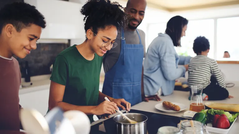 Famille multiraciale heureuse avec trois enfants cuisinant ensemble à la maison