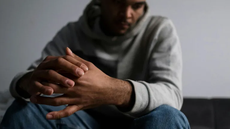 un homme triste, les mains jointes