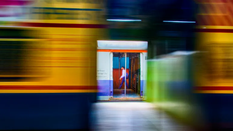 Un usager des transports en commun marche sur le quai tandis qu’un autre train de banlieue passe à toute vitesse, apparaissant flou sur la photo, à Mumbai, en Inde.