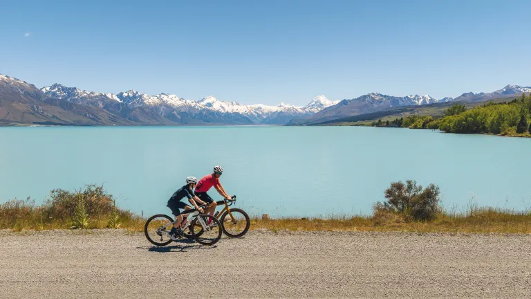 Vue en hauteur d'un homme et sa fille faisant du vélo à côté du lac Pukaki en été