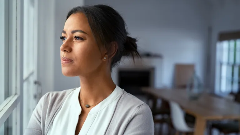 Une femme près d'une fenêtre a l'air déterminée.