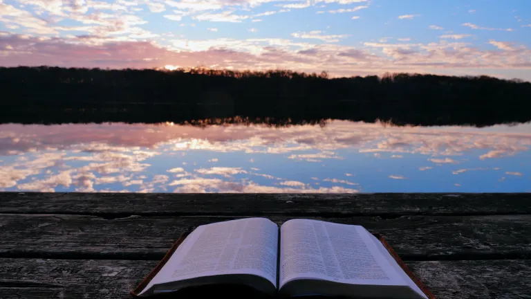 Une Bible avec le soleil qui se lève derrière des nuages sur un lac en arrière-plan